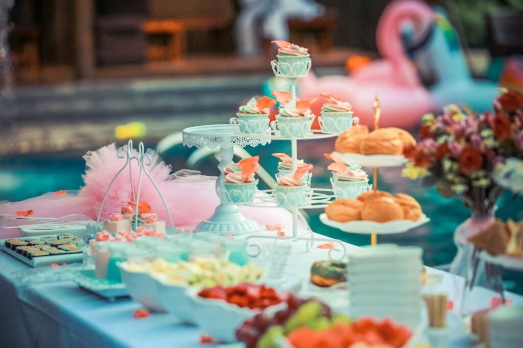 A beautifully arranged dessert table at an outdoor summer party near a pool.