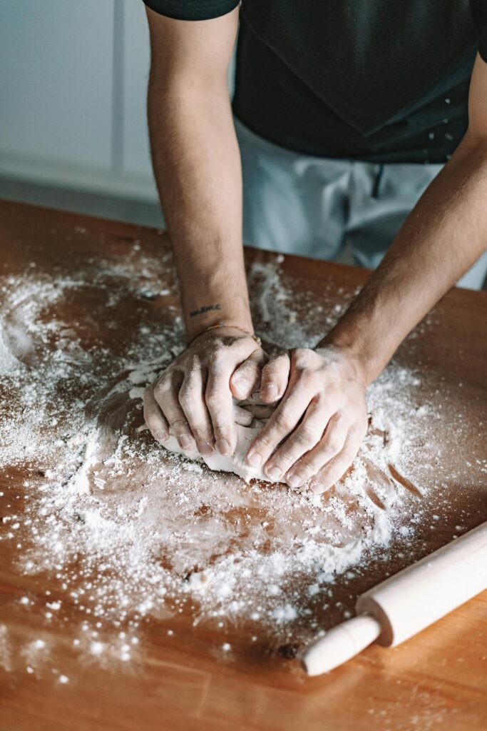 Close-up of hands kneading dough on a floured wooden table, capturing the essence of homemade baking.